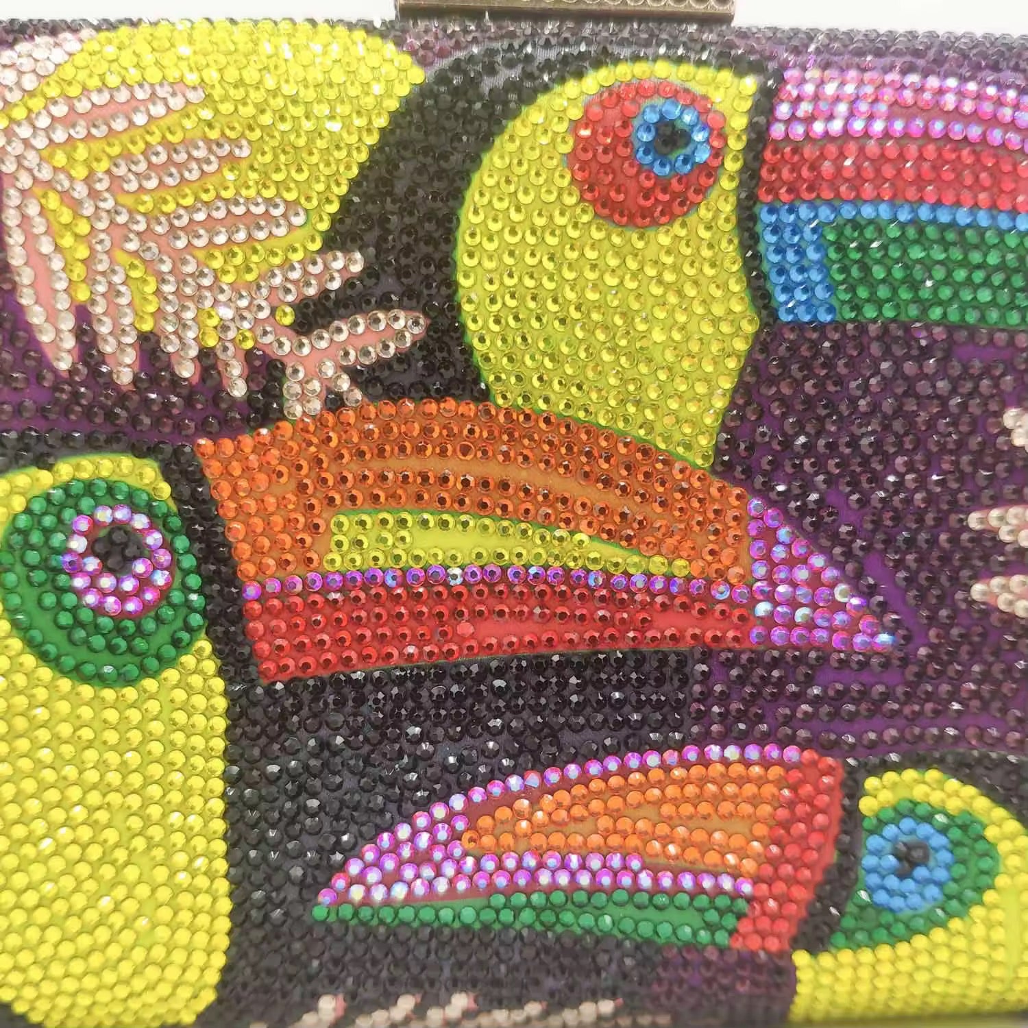 ŌMU – Strassbesetzte Clutch mit Toucan-Motiv